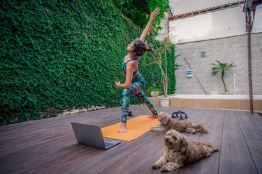 Woman doing a live-streaming workout on her deck with her dogs