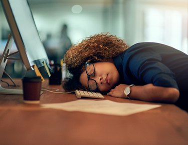 A young woman sleeping at her desk at work