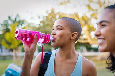 Sporty woman drinking from a reusable water bottle