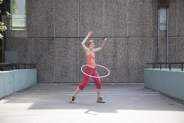 Woman hula hooping on city street