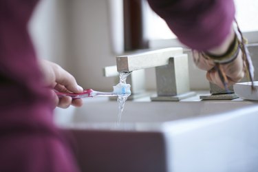 Man wetting toothbrush in sink to help with metallic taste in mouth