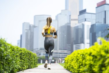 Sportswoman running in park, rear view