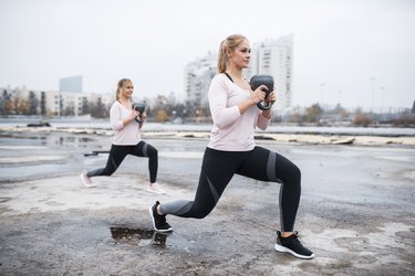 Two women lifting kettle bells outdoors