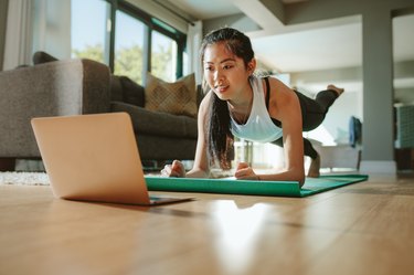 Woman in plank pose following along to a Pilates workout video