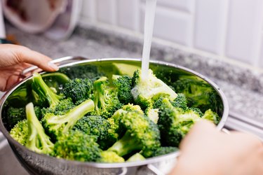 Woman washing broccoli in the kitchen sink