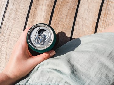 Can of soda in hand on wooden boardwalk