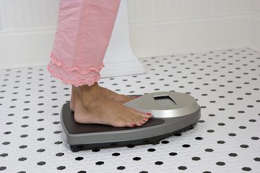 Person weighing themselves in their bathroom on a scale