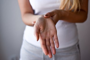 Closeup woman holds her wrist hand injury, feeling pain. Health care and medical concept