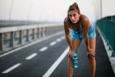 Exhausted athlete taking a water break from sports training outdoors.