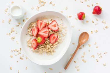 Oatmeal porridge with strawberries and milk in bowl