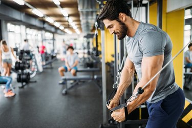 Man using the cable machine at the gym to work his chest during a full-body workout