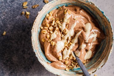 Vegan high fiber breakfast recipes with chocolate banana smoothie bowl with granola and nut butter, top view.