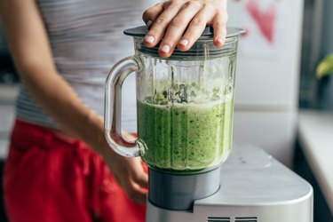 Close view of a woman on the Body Reset Diet blending a green smoothie