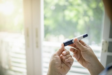 Close up of woman hands using lancet on finger to check blood sugar levels