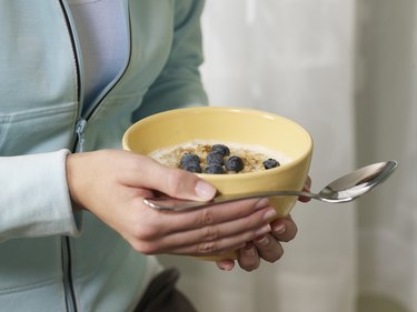 Woman holding bowl of oatmeal with blueberries