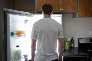 Man standing looking at contents of fridge