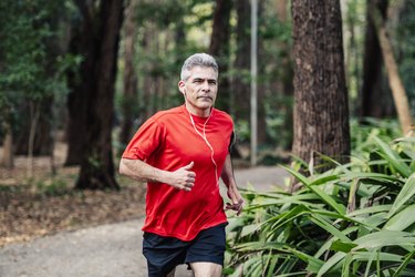 Mature man jogging in woods with earphones