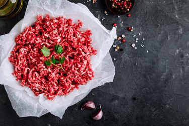Raw ground minced meat and seasonings on dark background