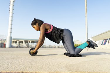 young sportive woman training with an ab wheel