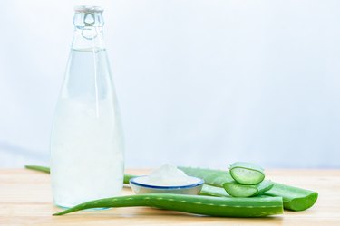 Fresh aloe vera leaves with aloe vera juice in bottle on wooden