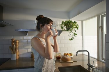 Person in a striped tank top drinking coffee mixed with benefiber in their kitchen