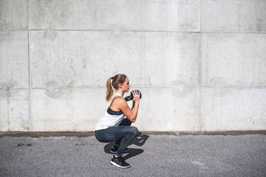 Woman doing squats with a kettlebell