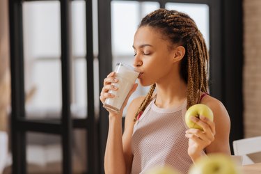 Young woman with little braids drinking glass of milk