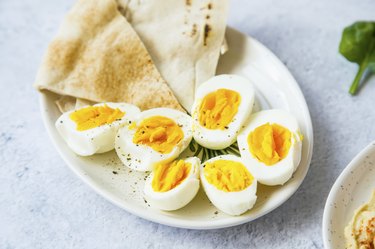 Boiled eggs cutted in halfs seasoned with pepper and salt with pita bread on a plate, healthy appetizers meal
