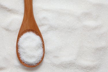 Wooden spoonful of white sugar just scooped up