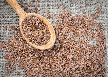 Flax seeds in a wooden spoon. Linseed is scattered.