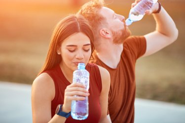 Modern couple taking pause in an urban park during jogging / exercise.