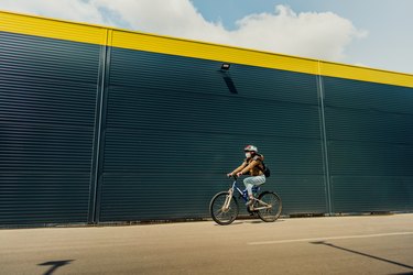 woman wearing helmet, face mask and backpack biking to work