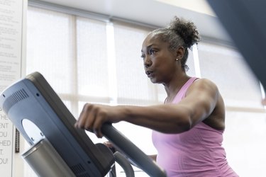 Mature person with ponytail and pink tank top doing a beginner elliptical workout