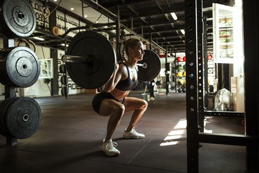 Woman squatting with a barbell.