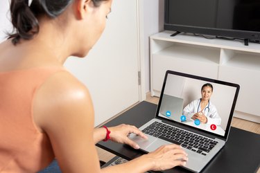 Woman using a laptop for a video call with a doctor