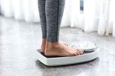 Person on a low-carb diet weighing themselves on a home scale