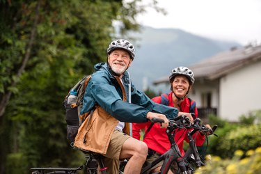 Senior couple tourist with bicycles cycling in town on holiday.