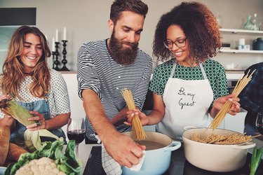 Friends making pasta for a meal-prep dinner together in the kitchen