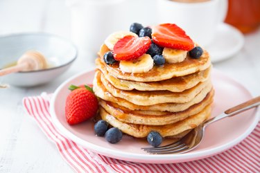 A stack of homemade pancakes with berries and banana slices