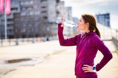 Female athlete drinking a water bottle after a workout