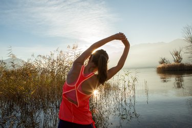 Beautiful and sporty young woman stretching after jogging outdoors