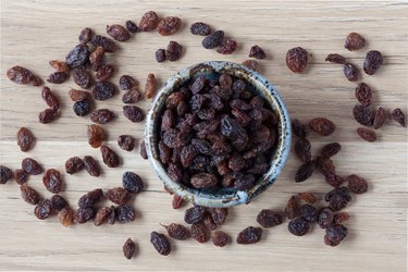 Organic raisins in bowl on wood