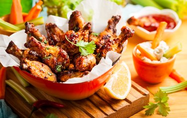 chicken wings with sauce in a red bowl on wooden table