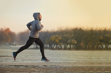 Young athletic man running at park during cold autumn morning