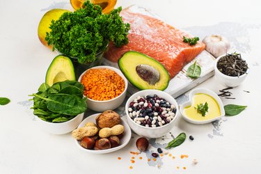 Variety of foods with carbohydrates, proteins and fat in bowls on white background