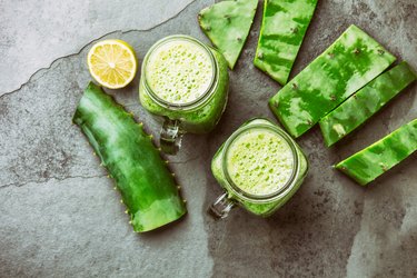 Healthy cactus nopales, aloe vera and lemon detox drink in jars and ingredients on gray background. Top view