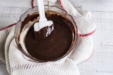 A bowl of chocolate brownie ingredients being stirred by a spatula.