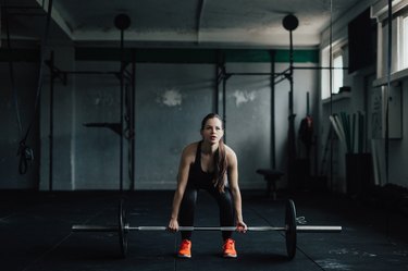 Determined young woman doing deadlift in the gym