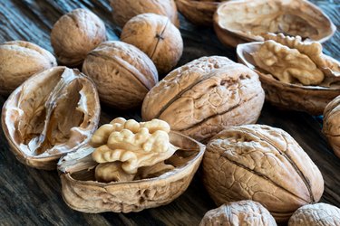 Whole and broken walnuts on a wooden background