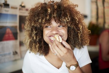 A black woman biting into a sandwich